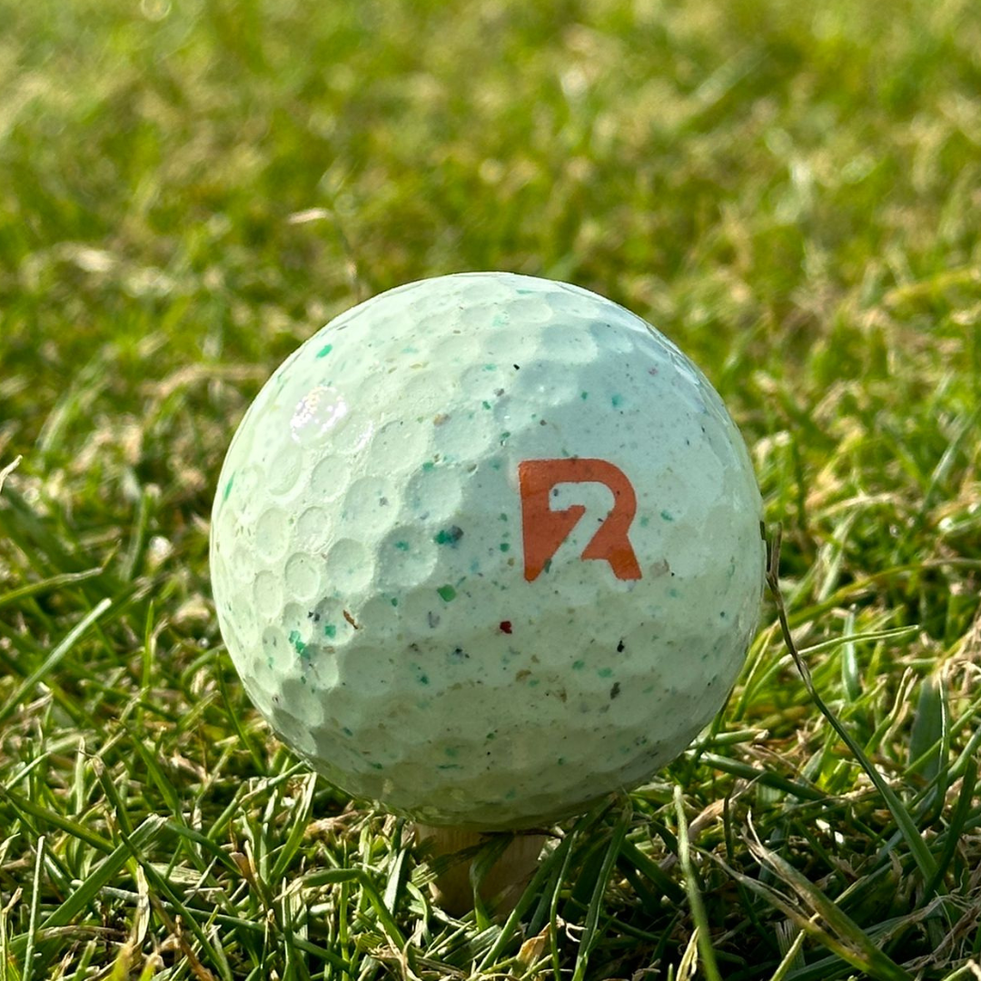 ROUND2 golf ball with alignment lines on green grass, ideal for new and junior golfers, offering distance and control with a sustainable design